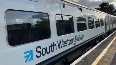 A white South Western Railway train at a station platform