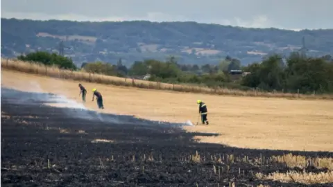 Fire crews use beaters to help tackle a fire in a dry agricultural field