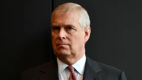 head and shoulders picture of Andrew Mounbatten-Windsor against a black background, he wears a suit and red tie, taken in Australia in 2018.