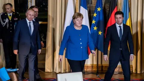 Getty Images Angela Merkel walks to the camera alongside Vladimir Putin and Volodymyr Zelensky at a meeting in Paris in 2019