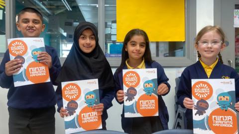 Aqeeh, Zoya, Naraz and Freya from Acacias Community Primary School hold up posters as part of the sun protection campaign