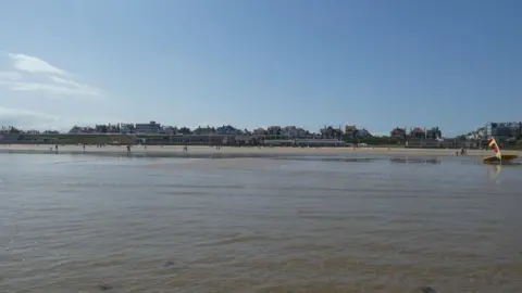 DS Pugh / Geograph A view from the sea showing Bridlington South Beach with beach huts by the shore and people paddling