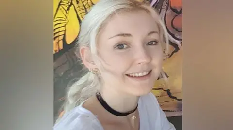Queensland Police Service A close-up image of a woman with blonde hair and blue eyes smiling at the camera.