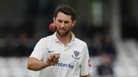 Fynn Hudson-Prentice tosses the ball in the air while bowling for Sussex