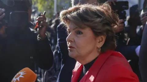 EPA Gloria Allred is wearing a red blazer and has a shoulder length brown bob hairstyle.