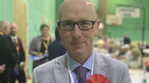 Patrick Hurley wearing a red Labour rosette