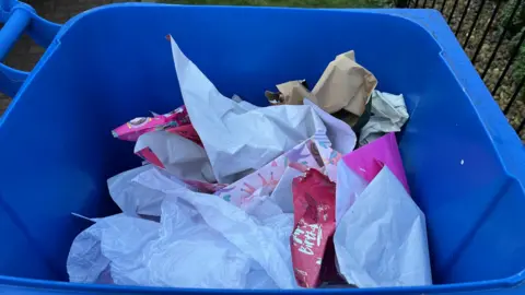 A blue bin containing paper