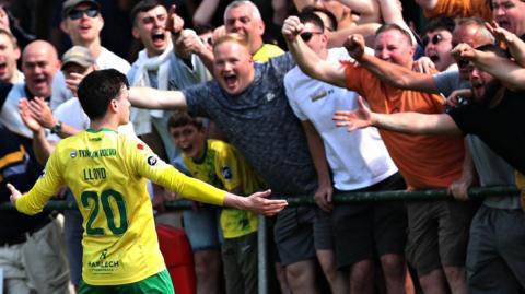 Louis Lloyd celebrates with fans after scoring Caernarfon's opening goal