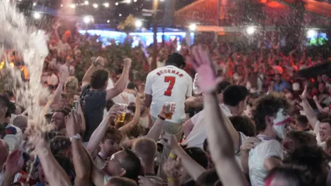 PA Media Fans throw beer into the air after an England goal with one fan in a Beckham shirt is carried by friend