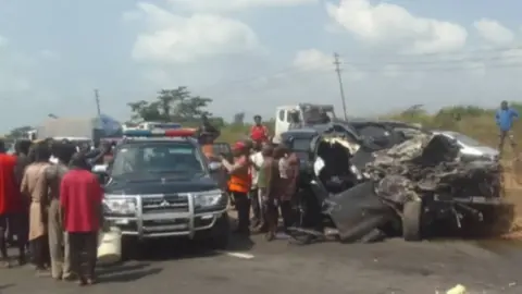 Cuerpo Federal de Seguridad en las Carreteras Una foto de un SUV negro estrellado junto a un vehículo de emergencia y una multitud de personas.