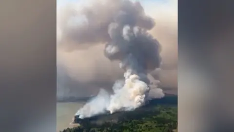 An enormous cloud of smoke billows over Cross Lake in Manitoba, Canada.