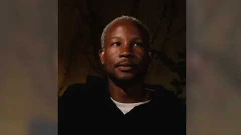 MUBI A man in a black hoodie with bleached blonde hair looks to the right of the camera