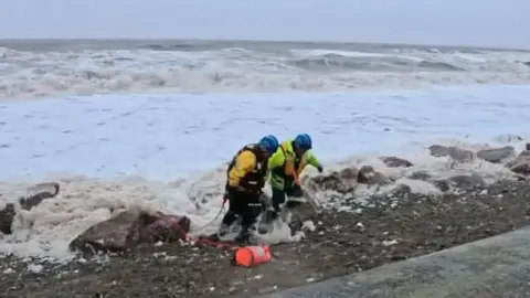 HM Coastguard Fleetwood Coastguards bringing the training dummy ashore at Cleveleys in Lancashire.