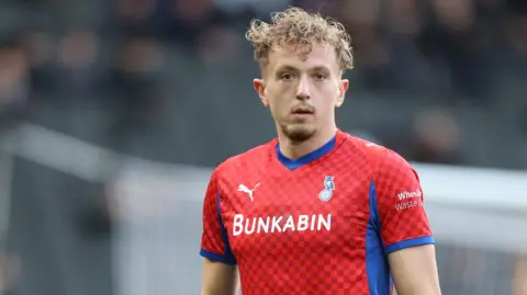 Michael Mellon wearing a red Oldham Athletic kit