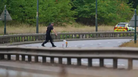 Owen Humphreys/PA Un agente de policía con uniforme negro cruza a pie la A66, que está completamente cerrada al tráfico.