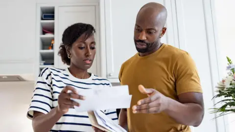 Getty Images A worried couple looking at a bill 