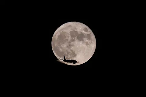 Tayfun Coskun/Anadolu Agency via Getty Image A plane passes in front of the moon