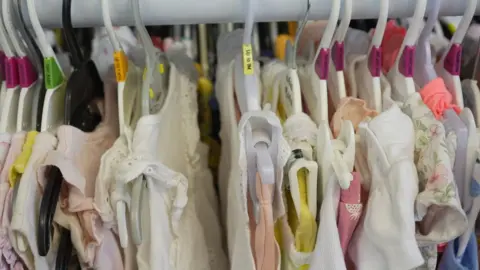 Jamie Niblock/BBC A clothes rail of baby clothes at Baby Basics' site