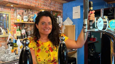 Colette Dewhurst, the landlady of The Barley Mow in Bonsall, standing inside the pub behind the bar