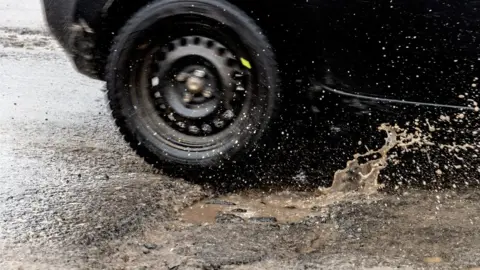 Getty Images Car tyre driving through wet pothole