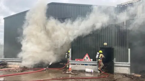 A warehouse with smoke billowing out of it