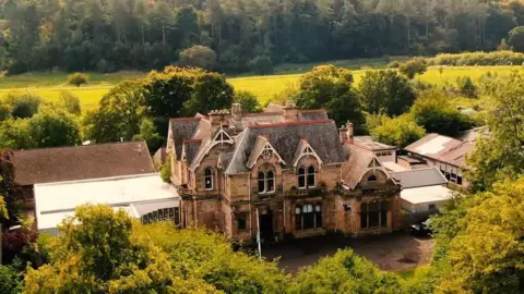 A large private school building surrounded by trees and grass
