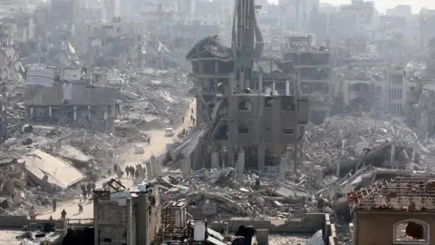 Reuters people walk on the debris of dead buildings, Injabalia, in the North Gaza Strip, on January 30, 2025