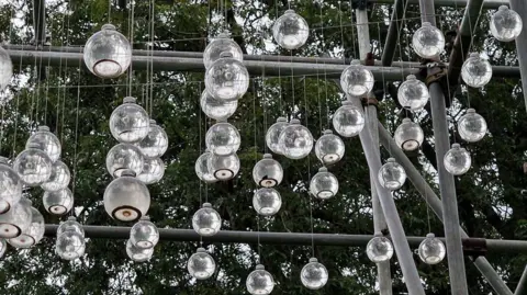 Dorset National Landscape Hundreds of spherical bottles of water and chalk sediment suspended by think cords from a metal frame