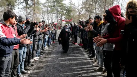 Getty Images Women Asylum Seekers, waiting at Turkey's Pazarkule border crossing to reach Europe, stage a demonstration at the buffer zone demanding they be permitted to cross during International Women's Day, 8 March 2020