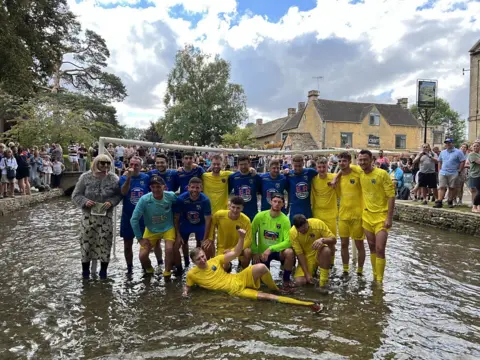 Players pose in the river for a team photo