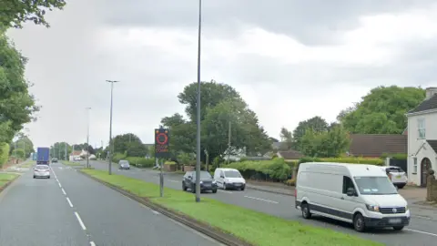 Dual carriageway with vehicles travelling along it and a 'Slow Down' sign