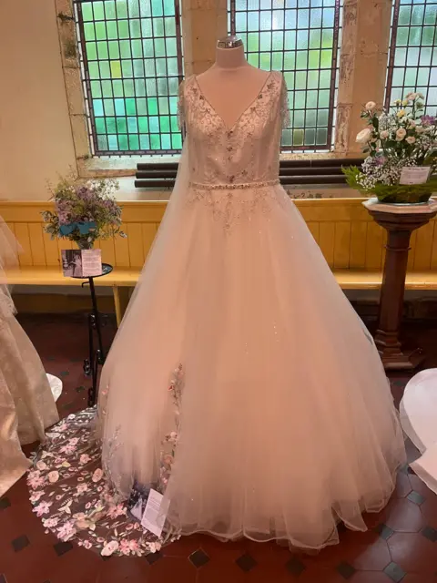 One dress on a mannequin in front of a church glass window