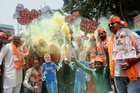 Getty Images BJP supporters let off smoke flares and are carrying a cutout of Indian Prime Minister Narendra Modi and shouting slogans to celebrate the day of the Lok Sabha election result in Varanasi,