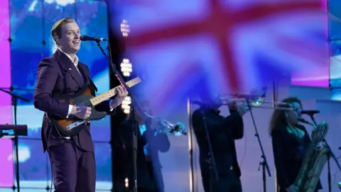 Joe Giddens George Ezra in front of a union flag on a screen