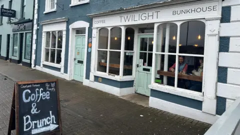A shop front of a cafe with thre name Twilight on teh signage. There is a blackboard on the footpath in front of the cafe advertising coffee and brunch and also indicating that the cafe is pet friendly.