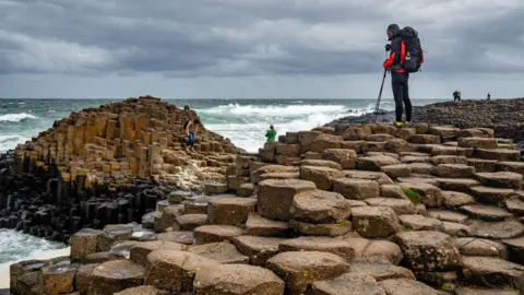 Ariel shot of the Giants causeway with people climbing over the rocks.