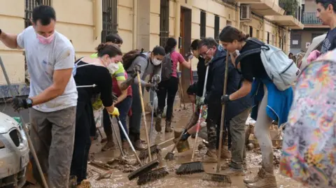 Getty Images Volunteers with brushes try to remove mud in Valencia 