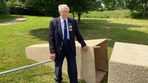 Dave Addis, branch secretary for the Royal British Legion, Long Ashton, stands next to the toppled cenotaph with a sombre expression. 