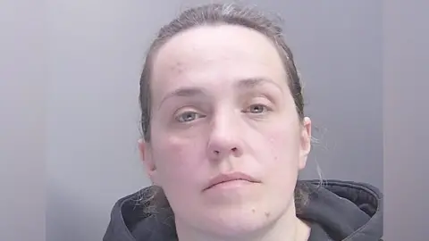 Cambridgeshire Constabulary Modesta Kelpsaite in a police custody shot looking at the camera. She has brown hair which is pulled back and is wearing a dark-coloured hooded top.