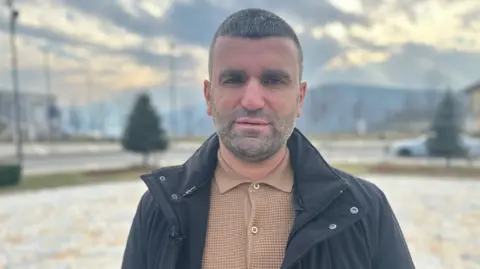 BBC Josie Hannett Albert Halilaj, the Mayor of Kukës, is standing outside a large roundabout in the middle of the town with mountains in the background 