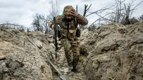 Getty Images A Ukrainian soldier runs into a trench outside Bakhmut