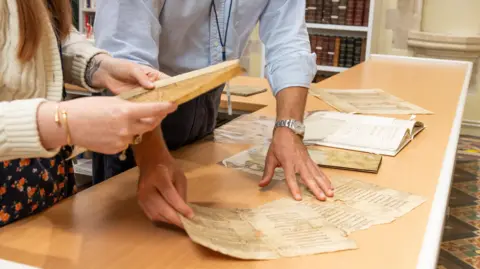 Max Rhydwen-Jones/States of Guernsey A man and woman sort through pieces of old text on a table 