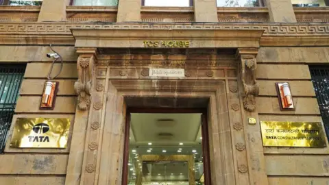 Getty Images image is the Mumbai headquarters of TCS. It is a colonial building decorated in brown stone, with gold panels of Tata and Tata Consultance services displayed on both sides of the main door.