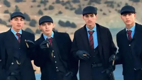 @tomasshelby.0093 Four Afghan men in three piece suits and flat caps hold cigars