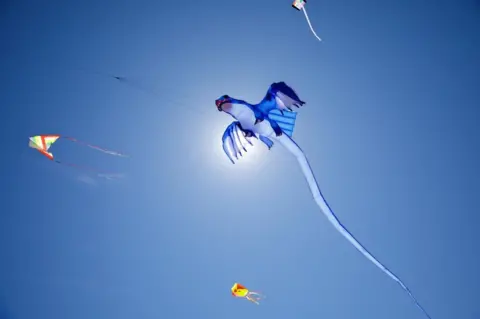 Getty Images People fly kites at the Dolphin Beach in Cape Town, South Africa.