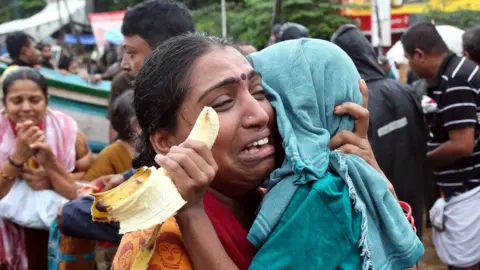 Reuters A woman cries as she holds her son after they were evacuated from a flooded area in Aluva - 18 August