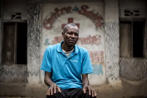 John Wessels / Oxfam Raphael sits outside a health clinic.