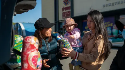 Joyce Liu/BBC Chinese vendor selling Russia-related paraphernalia at the border town