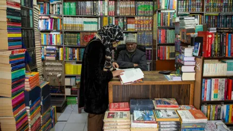 Faisal Bashir A woman is reading a book in a bookstore in Srinagar.