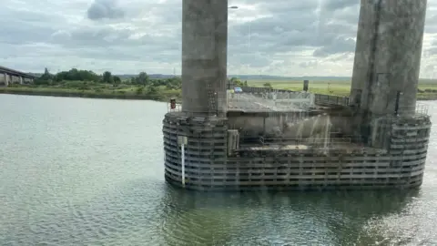 A concrete base of a bridge stretching over water. 
